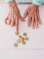 manos senior contando monedas de euro sobre la mesa. pobreza, crisis, depósito, concepto de recesión foto