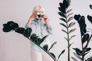 senior stylish woman with gray hair and in glasses and denim jacket taking pictures of flowers with film camera. Age, hobby, anti age, positive vibes, photography concept photo