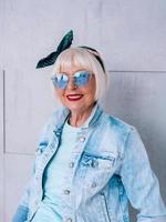 mujer elegante senior con cabello gris con diadema de moda y gafas azules. moda, anti edad, relax, vacaciones, concepto de jubilación foto