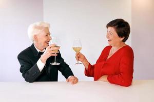 Two beautiful stylish mature senior women drinking wine in bar. Fun, party, style, celebration photo