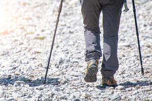 Detail of mountain walker on stony road with Nordic walking sticks photo