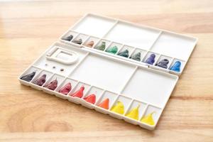 Watercolor paints set. Color in watercolor palette with wooden background. photo