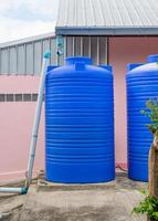 Tanque de agua de plástico azul en el área de la casa. foto