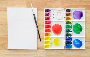 pinturas de acuarelas en paleta blanca con papel blanco para el fondo. foto