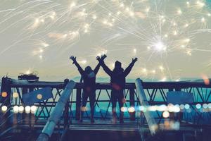 amantes de las mujeres y los hombres asiáticos. ponte de pie y levanta las manos para ver los fuegos artificiales. feliz en el día de la celebración del día de año nuevo en la montaña en tailandia. foto