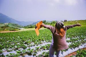 Asian woman travel nature. Travel relax. Girl reading a book In the vegetable garden. Nature Education Write a note in the garden Strawberry. Thailand photo