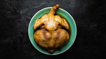 vista desde arriba de pollo entero en la mesa. Pollo entero asado en un plato verde.