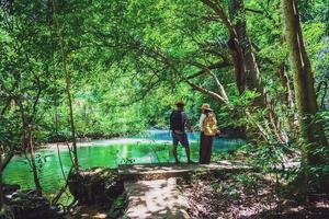 viajeros, parejas con mochilas de viaje naturales durante las vacaciones. parejas viajando, relajándose en la jungla verde y disfrutando del hermoso estanque esmeralda. turismo, senderismo, estudio de la naturaleza.