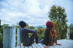 pareja amante viajes naturales en la montaña, sentarse relajarse leyendo libros en medio de la naturaleza en el puente de madera blanca. foto