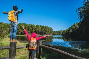 Couples travelers with backpack happy to relax on a holiday, travelers Pang-Ung park travel,Travel to visit nature landscape the beautiful at lake, at Mae-hong-son, in Thailand.