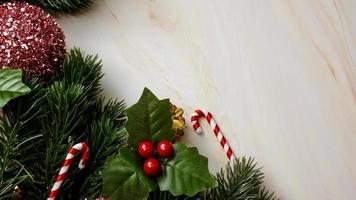 hojas de pino verde, adornos navideños rosas y bastones de caramelo sobre fondo de mármol suave, adornos navideños en color rosa brillante y elegante. concepto de navidad simple y creativo.