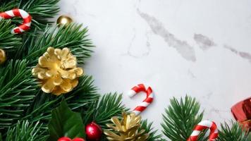 Green pine tree leaves, red christmas decorations and candy canes on white marble background, christmas decorations in bright red color. Simple and creative christmas concept. photo