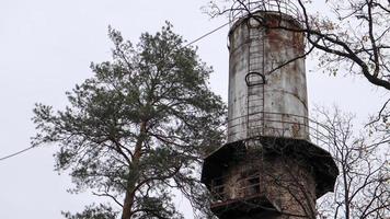 el tubo de la planta se eleva sobre el bosque. paisaje industrial. producción ecológica sin humo de pipas. torre de agua en el pueblo. Abastecimiento de agua a las casas bajo presión. paisaje rural. foto