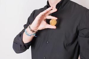 joven anónimo mostrando un bitcoin dorado. conceptos de riesgo, inversión, futuro