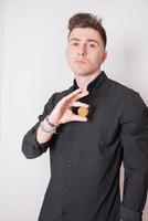 Young man showing a bitcoin. Dressed in black, white background. photo