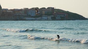 vista panorámica de la playa de san lorenzo en gijón. una persona surfeando y la ciudad vieja al fondo. asturias, españa foto