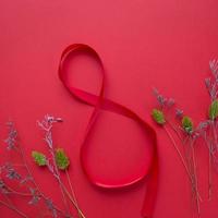 Satin red ribbon in the form of 8 on a red background photo