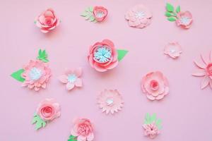 Different pink paper flowers on pink background photo