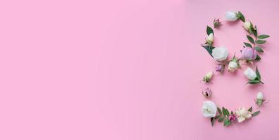 Figura 8 hecha de diferentes flores sobre fondo rosa. foto