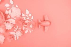 concepto de viaje con avión de madera y flores de papel, pétalos sobre fondo rosa. foto