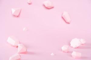 A variety of faceted gemstones, made of paper on a pink background. photo