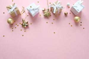 Christmas background with decorations and gift boxes on pink background photo