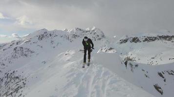 Bergsteigender Skifahrer kommt auf den Gipfel des Berges und entfernt die Felle