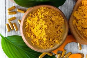 Turmeric powder in white cup on wooden floor photo