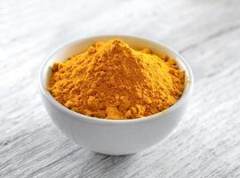 Turmeric powder in white cup on wooden floor photo