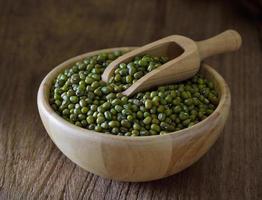 Gramo verde o frijol mungo en un tazón de madera sobre la mesa foto