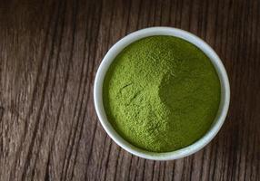 Green tea powder in cup on wood table photo