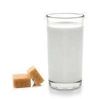 Vaso de leche y cubos de azúcar de caña aislado sobre fondo blanco. foto