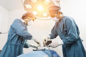 cirujano que opera al paciente con un asistente en el quirófano. concepto de cirugía y emergencia foto