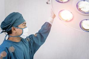 Asistente de cirujano preparando lámparas quirúrgicas en el quirófano