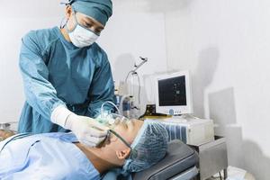 El cirujano asistente puso al paciente en una máscara de oxígeno y ventilador en preparación para la cirugía. foto