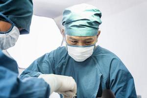 cirujano que opera al paciente con un asistente en el quirófano. concepto de cirugía y emergencia foto
