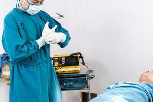 Doctor wearing gloves preparing before the surgery in the operating room photo