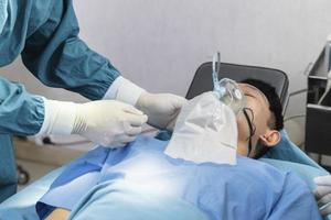 assistant surgeon put the patient on a ventilator-oxygen mask in preparation for surgery. photo