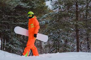 Snowboarder walking through the forest photo