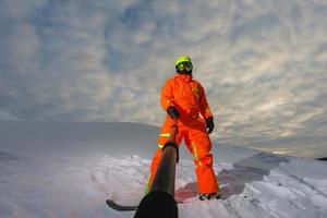 Snowboarder with the snowboard making a selfie photo