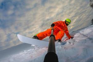 Snowboarder doing a trick and making a selfie photo