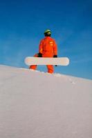 Snowboarder freerider with white snowboard standing on the top of the ski slope photo