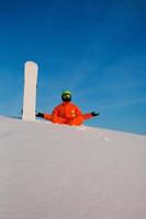 Snowboarder freerider with white snowboard sitting on the top of the ski slope photo