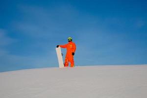 Snowboarder freerider with white snowboard standing on the top of the ski slope photo
