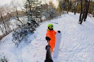 Snowboarder with the snowboard making a selfie photo