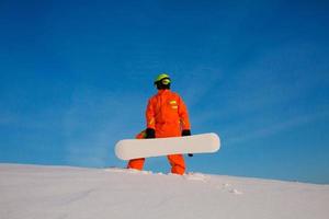 Snowboarder freerider with white snowboard standing on the top of the ski slope photo