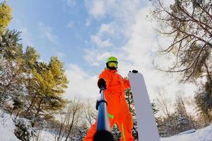 Snowboarder with the snowboard making a selfie photo