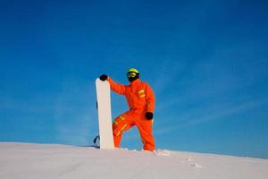 Snowboarder freerider with white snowboard standing on the top of the ski slope photo