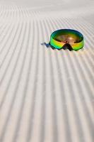 Ski goggles laying on a new groomed snow and empty ski slope photo