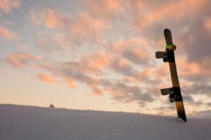 Textura en polvo y equipamiento para hacer snowboard al atardecer. foto